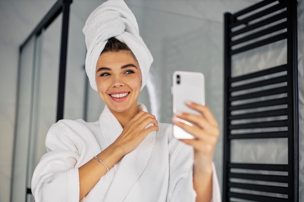 Jonge vrouw die schoonheid doet leven met haar telefoon