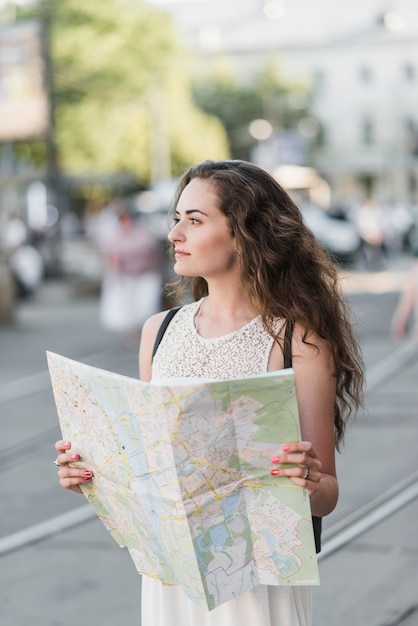 Jonge vrouw die stad met kaart onderzoekt