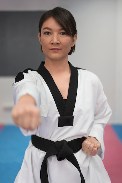 Gratis foto jonge vrouw die taekwondo beoefent in een gymnasium