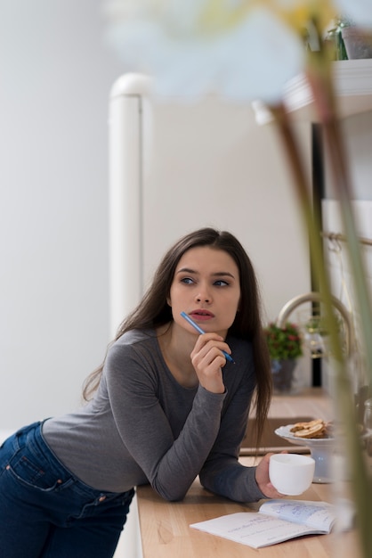 Jonge vrouw die terwijl het hebben van koffie denkt