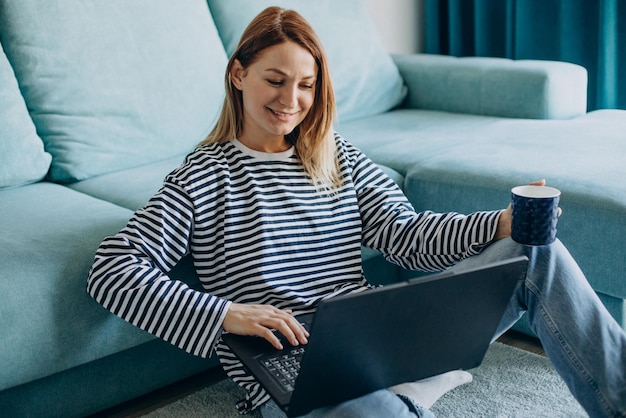 Jonge vrouw die thuis op haar laptop werkt en studeert