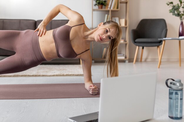 Jonge vrouw die thuis op mat uitoefent