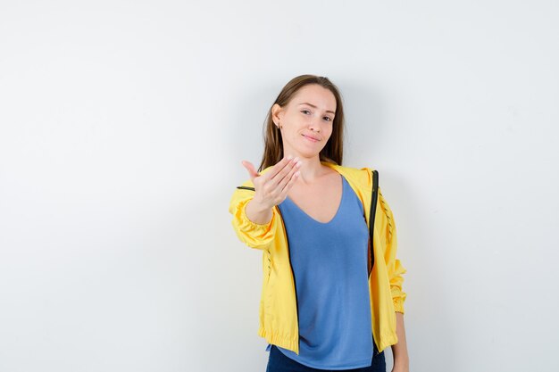 Jonge vrouw die uitnodigt om in t-shirt, jas te komen en er zelfverzekerd uitziet. vooraanzicht.