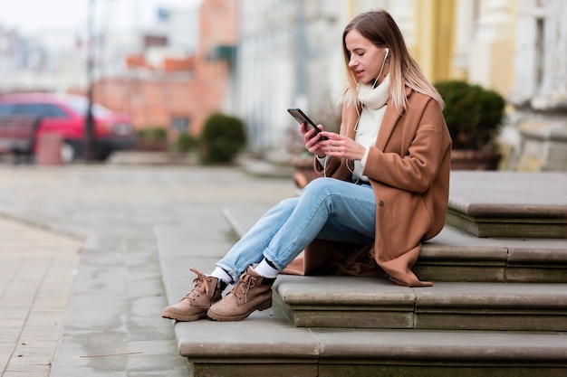 Jonge vrouw die van de muziek op oortelefoons in de stad geniet