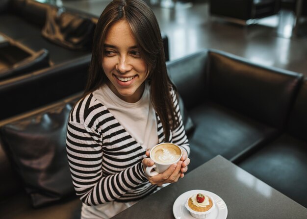 Jonge vrouw die van een koffiekop geniet