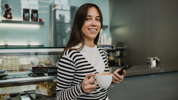 Jonge vrouw die van een koffiekop geniet