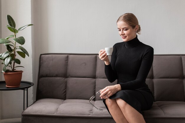 Jonge vrouw die van kop van koffie geniet