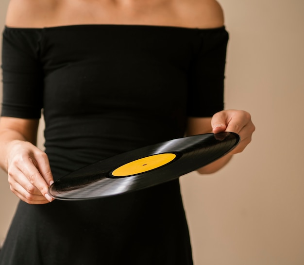 Gratis foto jonge vrouw die vinylverslag met beide handen houdt