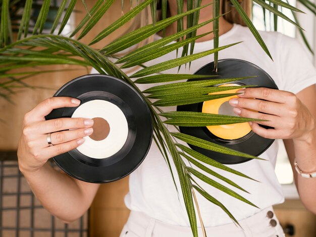 Jonge vrouw die vinylverslagen in beide handen achter installatie houdt