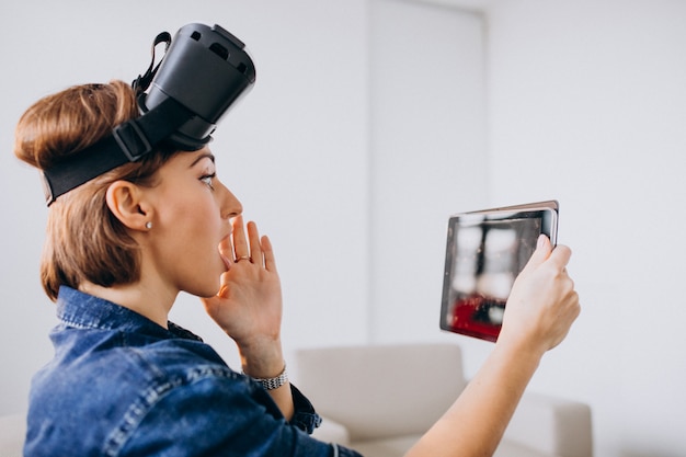 Gratis foto jonge vrouw die vr glazen draagt en tablet gebruikt