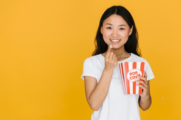 Gratis foto jonge vrouw die wat popcorn met exemplaarruimte heeft