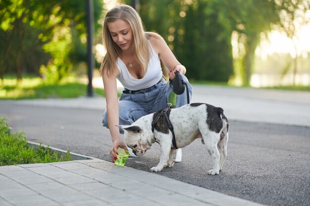 Jonge vrouw die water geeft aan hond in park