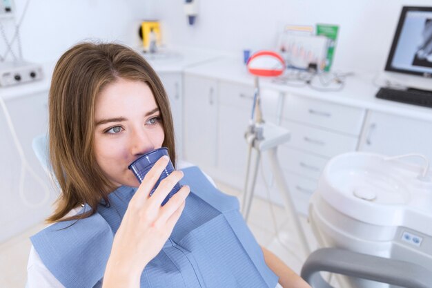 Jonge vrouw die water neemt terwijl het zitten als tandvoorzitter
