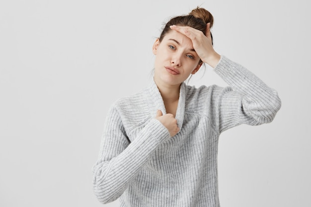 Jonge vrouw die wollen warme sweater draagt die heet wat betreft haar hoofd is dat probeert zich uit te kleden. Vrouwelijke SEO-specialist die een gebrek aan frisse lucht voelt en ontevredenheid uitdrukt. Sensation concept