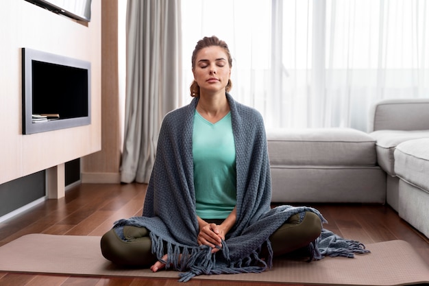 Jonge vrouw die yoga beoefent om te ontspannen
