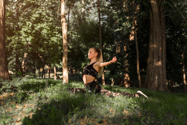 Jonge vrouw die yoga in het park doet