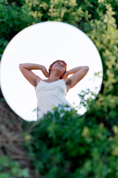 Jonge vrouw die zelfverzekerd buiten poseert met een ronde spiegel