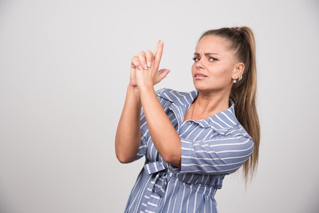 Jonge vrouw die zich agressief op grijze muur bevindt.