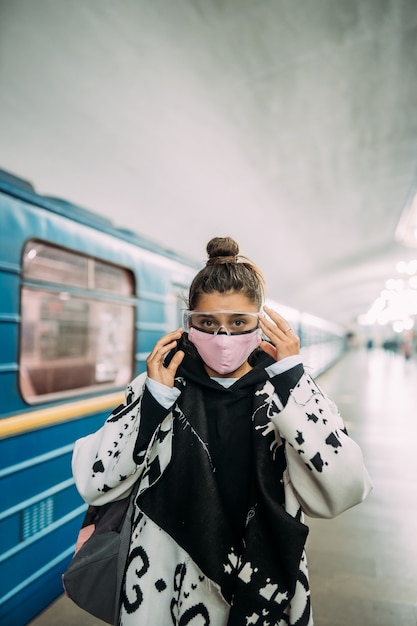 Jonge vrouw die zich bij station in medisch beschermend masker bevindt