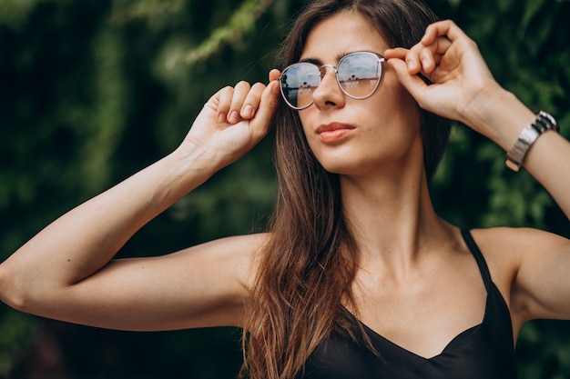 Gratis foto jonge vrouw die zich door de groene struiken bevindt