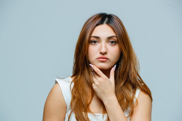 Jonge vrouw die zich voordeed met de hand op de kin en er serieus uitziet