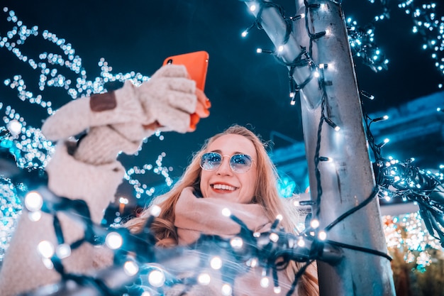 Jonge vrouw die zich voordeed op de straat met verlichte bomen