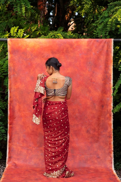 Gratis foto jonge vrouw die zich voordeed terwijl ze een traditioneel sari-kledingstuk draagt