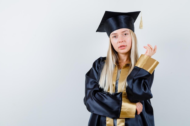 Jonge vrouw die zich voordeed terwijl ze naar de camera keek in een afgestudeerd uniform en er schattig uitzag.