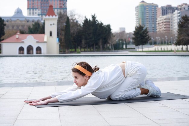 Jonge vrouw doet haar oefeningen op yogamat in het park Foto van hoge kwaliteit