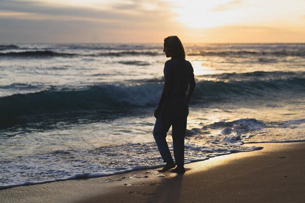 Jonge vrouw door de oceaan bij zonsondergang.