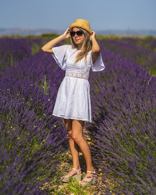 Jonge vrouw draagt een mooie jurk die op een zonnige dag in een veld met lavendel loopt