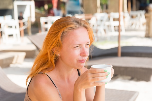 Jonge vrouw drinken koffie op het strand