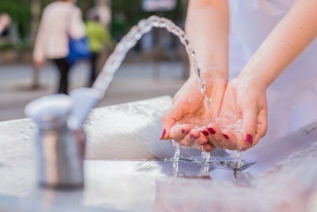 Jonge vrouw drinkwater uit de fontein