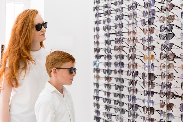 Gratis foto jonge vrouw en jongen die zich in opticenshowroom verenigen