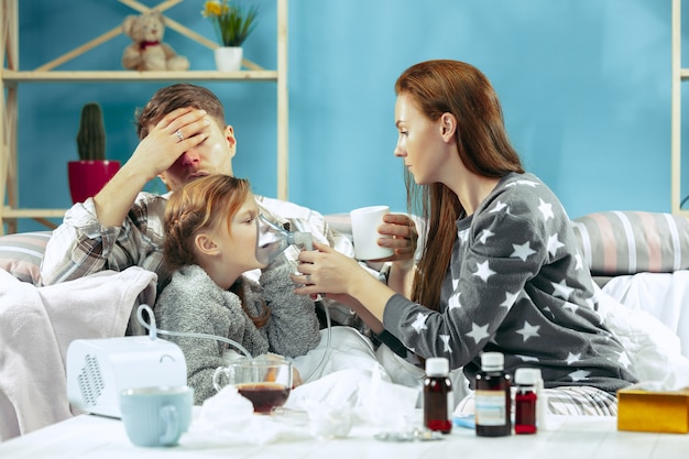 Gratis foto jonge vrouw en man met zieke dochter thuis. thuisbehandeling. vechten met een ziekte. medische gezondheidszorg.