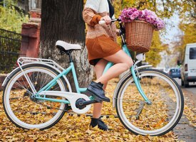 Gratis foto jonge vrouw fietsten met bloemen op herfst straat