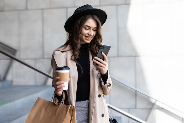 Jonge vrouw gebruik van mobiele telefoon en boodschappentas in de straat te houden