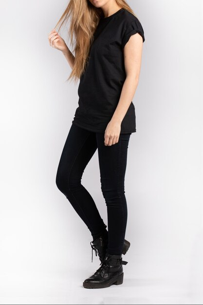 Jonge vrouw, gekleed in zwarte korte mouw t-shirt staande tegen een witte muur