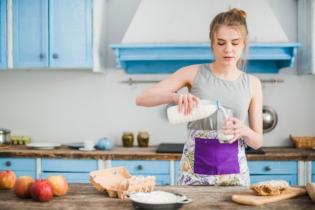 Jonge vrouw gieten melk in glas