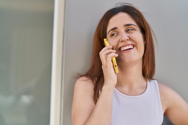 Gratis foto jonge vrouw glimlachend zelfverzekerd praten op de smartphone op straat