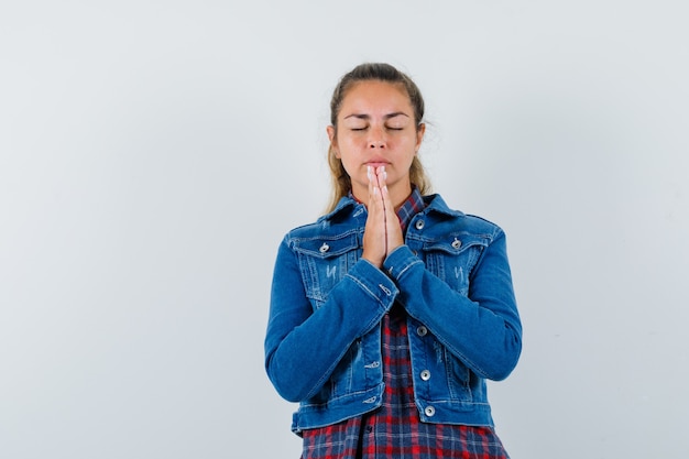 Jonge vrouw hand in hand biddend gebaar in overhemd, jasje en op zoek hoopvol, vooraanzicht.