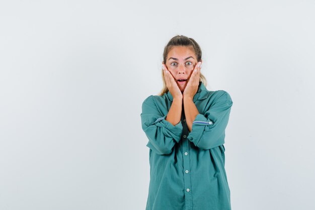 Jonge vrouw hand in hand om in groene blouse onder ogen te zien en verbaasd te kijken