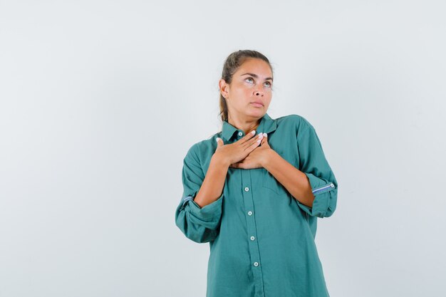 Jonge vrouw hand in hand op de borst in groene blouse en schattig kijken