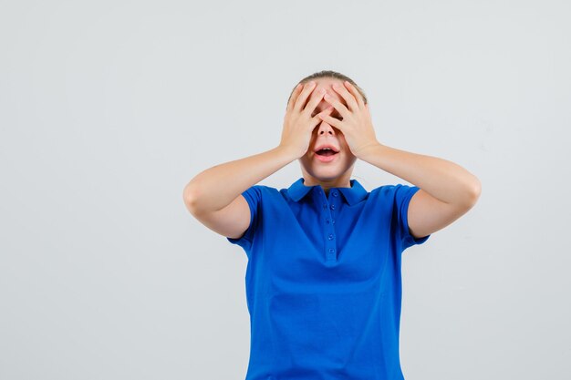 Jonge vrouw hand in hand op gezicht in blauw t-shirt en hoopvol kijkt