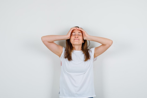 Jonge vrouw hand in hand op het hoofd in wit t-shirt, korte broek en op zoek ontspannen. vooraanzicht.