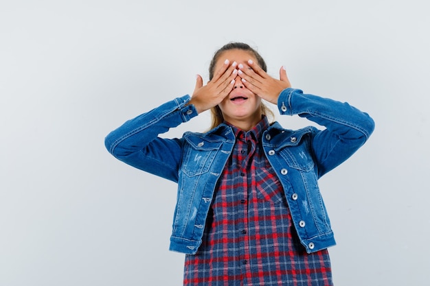 Jonge vrouw hand in hand op ogen in shirt, jasje en opgewonden, vooraanzicht kijken.