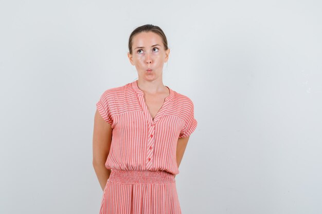 Jonge vrouw hand in hand op rug in gestreepte jurk en peinzend, vooraanzicht op zoek.