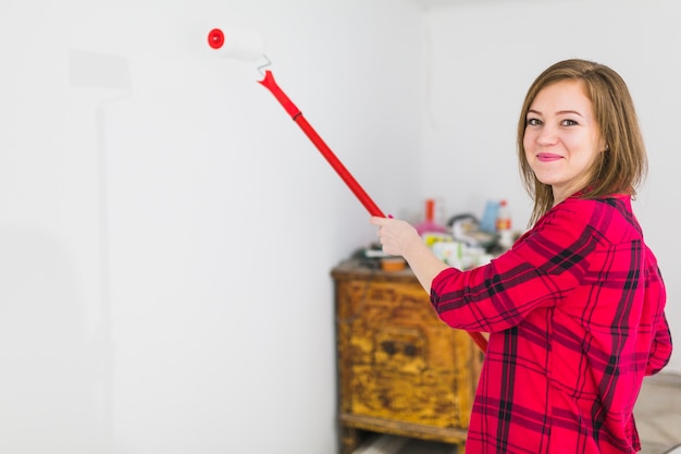 Gratis foto jonge vrouw het schilderen muur en het bekijken camera