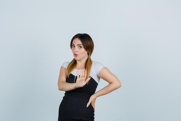 Jonge vrouw houdt hand op heup terwijl ze stopbord toont