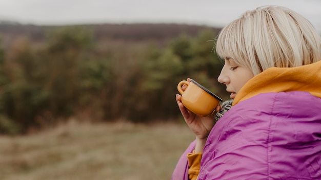 Gratis foto jonge vrouw in aard het drinken thee